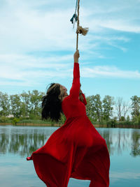 Rear view of woman standing against lake