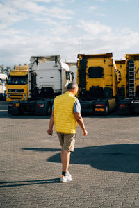 Rear view of man walking on road against sky