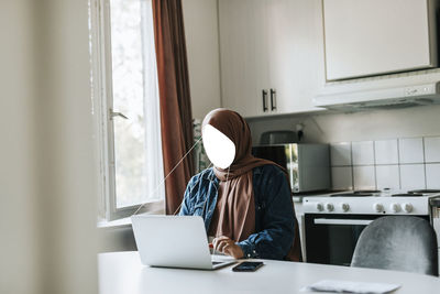 Faceless woman using laptop at home