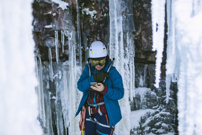 Female ice climber using cell phone