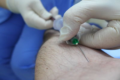Close-up of doctor injecting syringe in patient arm