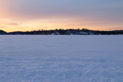 Scenic view of snow covered field against sky at sunset