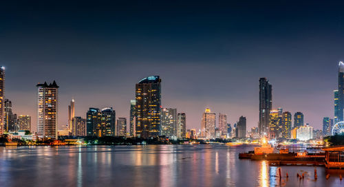 River by illuminated buildings against sky at night