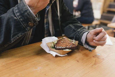 Midsection of man holding ice cream on table in restaurant