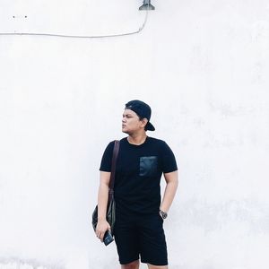 Young woman standing against wall