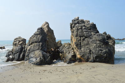 Rock formations on beach against sky