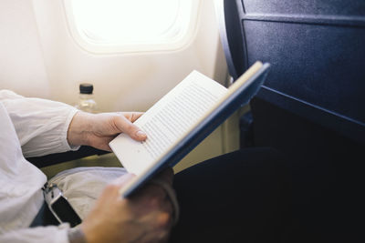 Midsection of man using mobile phone in airplane