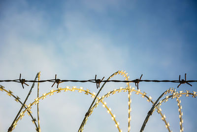 Low angle view of barbed wire against sky