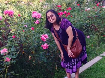 Portrait of smiling woman standing by pink flowering plant