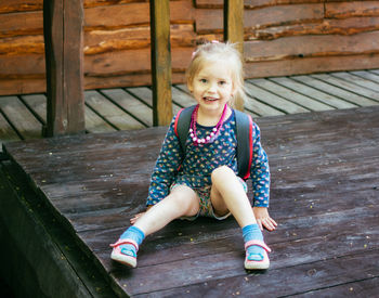 Portrait of happy girl sitting on wood