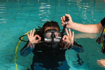 Instructor assisting woman in scuba diving in swimming pool