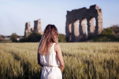 Rear view of woman standing on field against sky