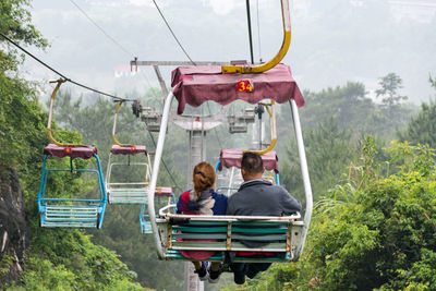 Rear view of man and woman sitting on overhead cable car