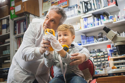 Grandfather and boy repairing computer part on table at home