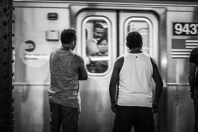 Rear view of men walking in train