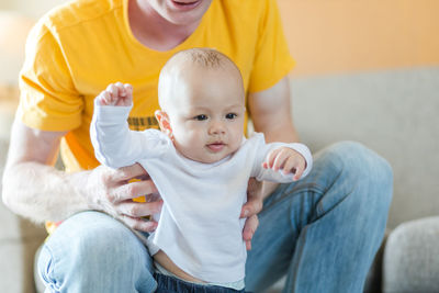 Midsection of father holding cute son at home