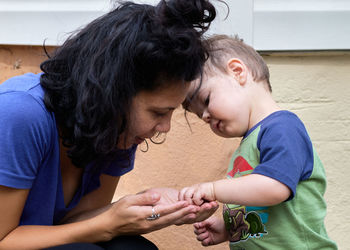 Cute little toddler is playing pebbles with mom on the back porch