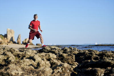 Mature man running on rocks at beach