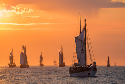 Sailboat sailing on sea against orange sky