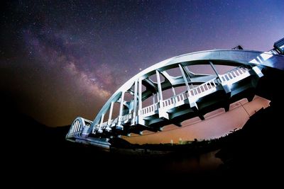 Low angle view of arch bridge over river against star field