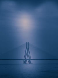 Suspension bridge over sea against sky during sunset