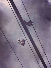Low angle view of power lines against cloudy sky