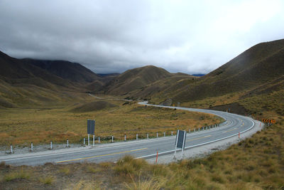 Scenic view of road by mountains against sky