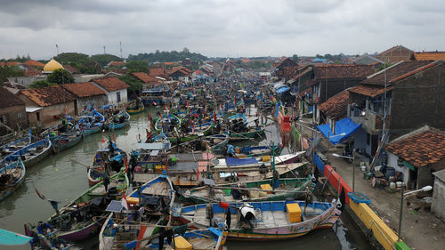 High angle view of boats moored at harbor by buildings in city