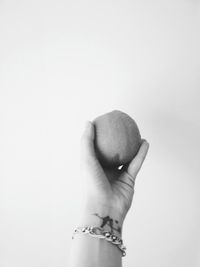 Cropped hand holding orange against white background