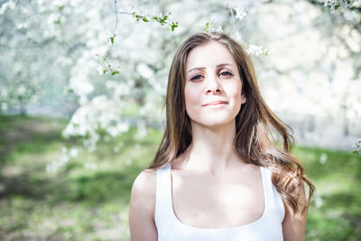 Cheerful long hair young woman in a white t-shirt under the blooming trees. spring park 