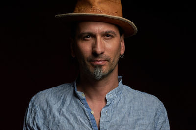 Portrait of man wearing hat against black background