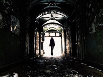 Rear view of people walking in tunnel