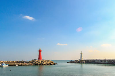 Lighthouse by sea against sky