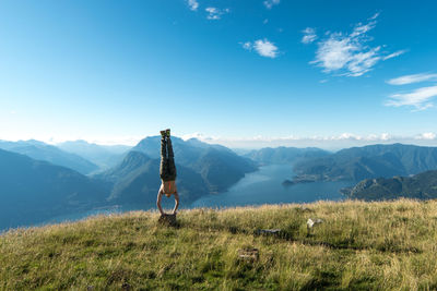 Rear view of man standing on mountain against blue sky