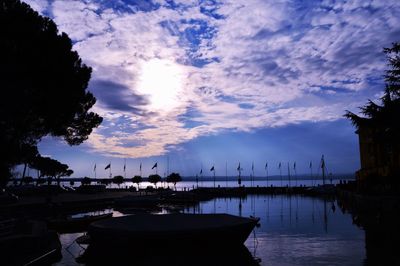 Silhouette of boats in sea against cloudy sky