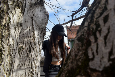 Woman standing by tree trunk