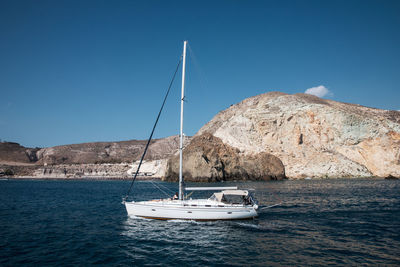 Sailboat sailing on sea against clear blue sky