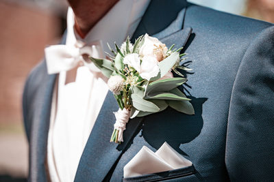 Midsection of bridegroom wearing boutonniere
