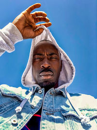 Low angle portrait of man against blue sky