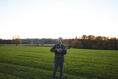 Rear view of man standing on field against clear sky
