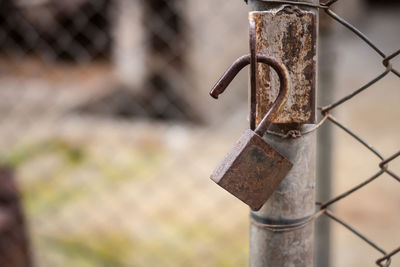 Close-up of rusty chain hanging on metal fence