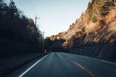 Road amidst trees against clear sky