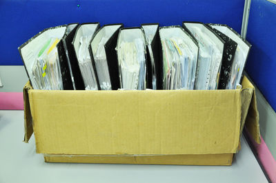 Close-up of papers in cardboard box on table