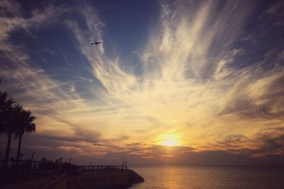 Scenic view of sea against dramatic sky during sunset