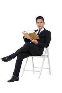 Young man sitting on chair against white background