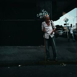 Full length of young woman standing against wall at night