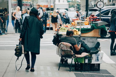 Rear view of people walking on street in city