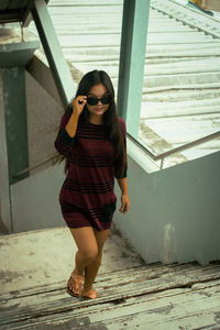 Portrait of young woman standing against wall