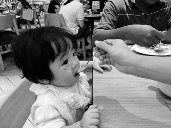 Cropped hand of mother feeding daughter in restaurant