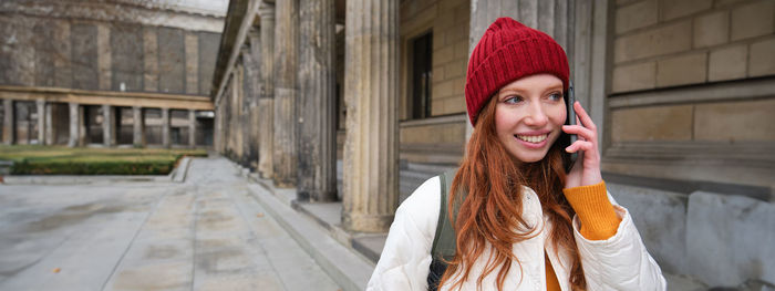 Portrait of young woman standing against wall